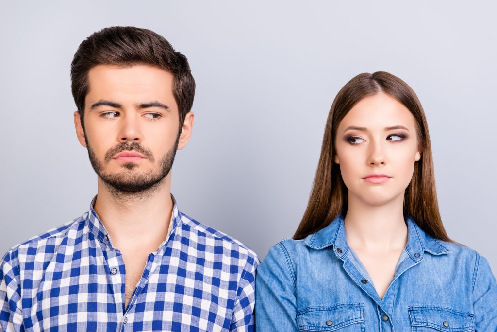 Mistrust and cheat problems Annoyed couple is ignoring each other but spy each other secretly they stand on pure background in casual shirts