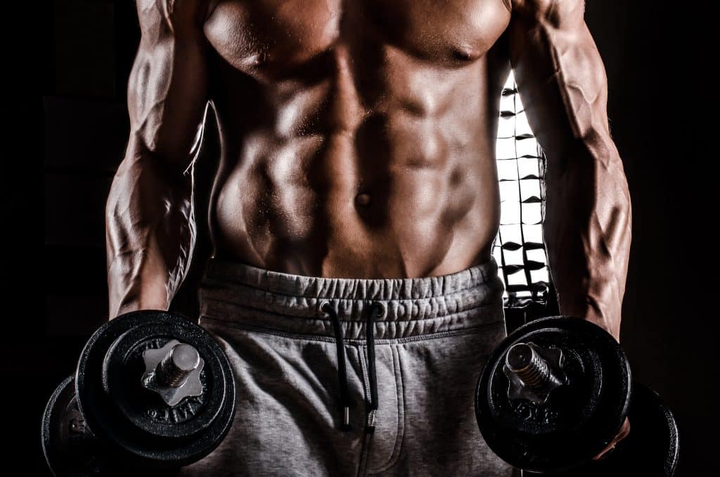 Powerful Body of Athlete Bodybuilder Posing with Dumbbells