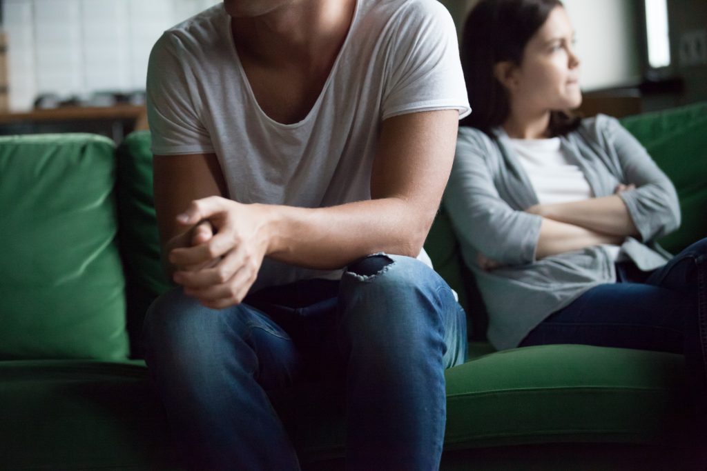 Unhappy couple sitting on couch at home