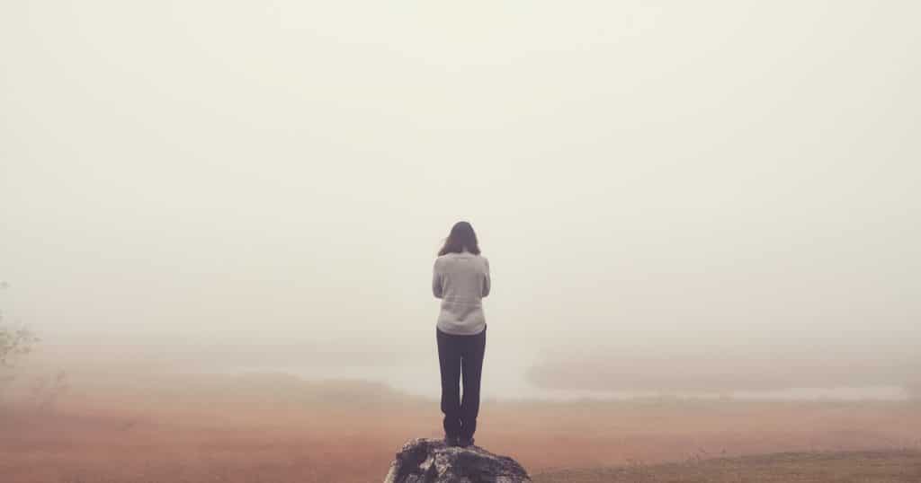 Depressive Frau steht an der Klippe und denkt an Selbstmord.