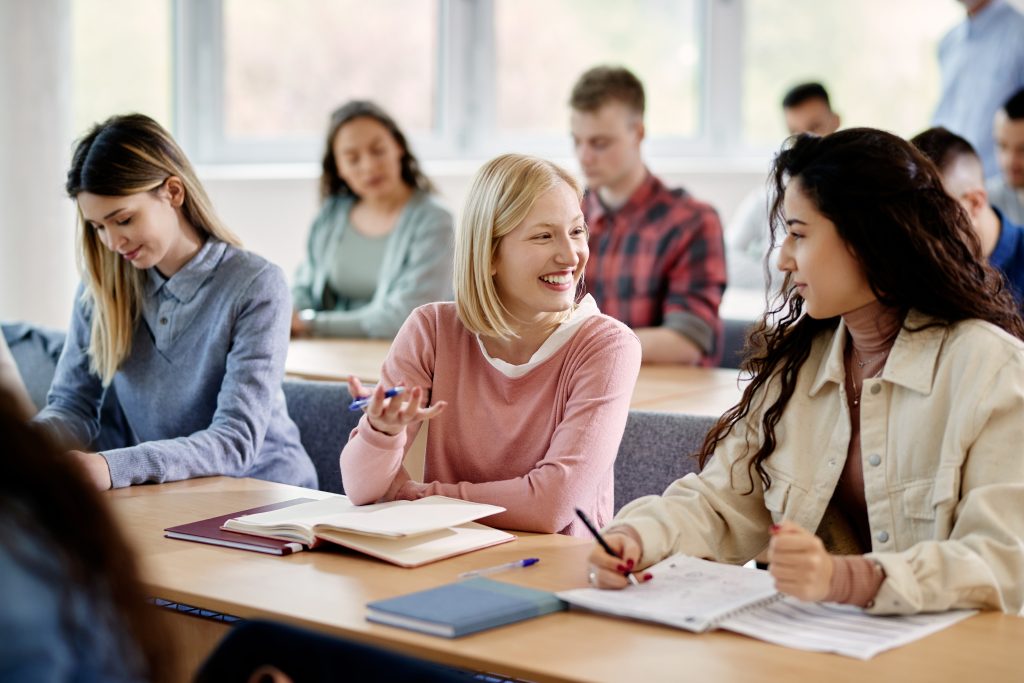 Happy female students talk while attending lecture at the university.