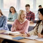 Happy female students talk while attending lecture at the university.