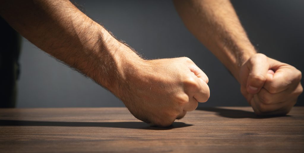 Fists of angry man beats on the table.