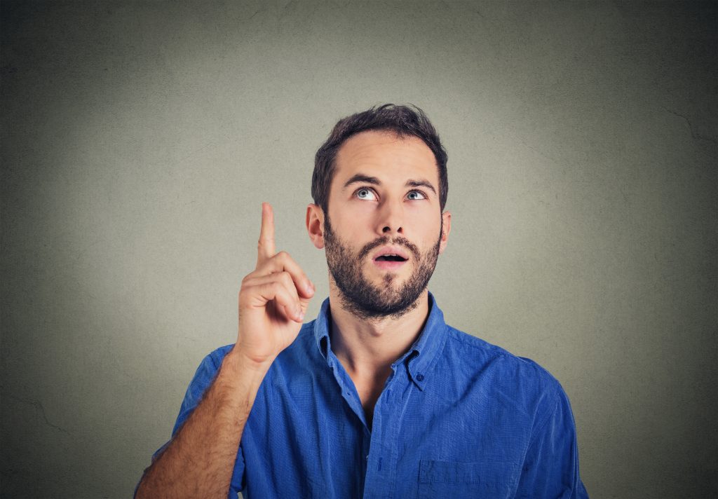 young man has an idea, pointing with finger up looking up