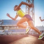 Two female sprinter athletes running on the treadmill race during training in athletics stadium.